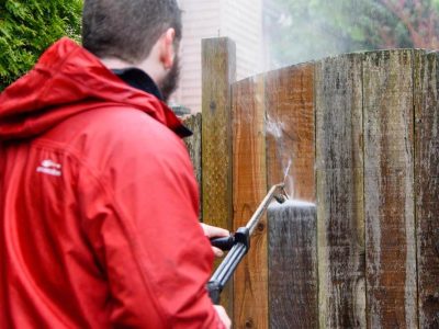 Sky Power Wash professional in red jacket pressure washing fence