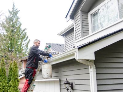 Sky Power Wash professional in blue gloves cleaning gutters